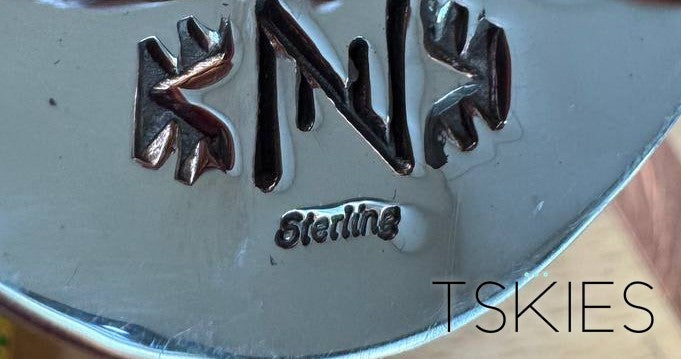 Nick Nez hallmark on a sterling silver bolo tie — a single N flanked by matched stamps, with Sterling struck below